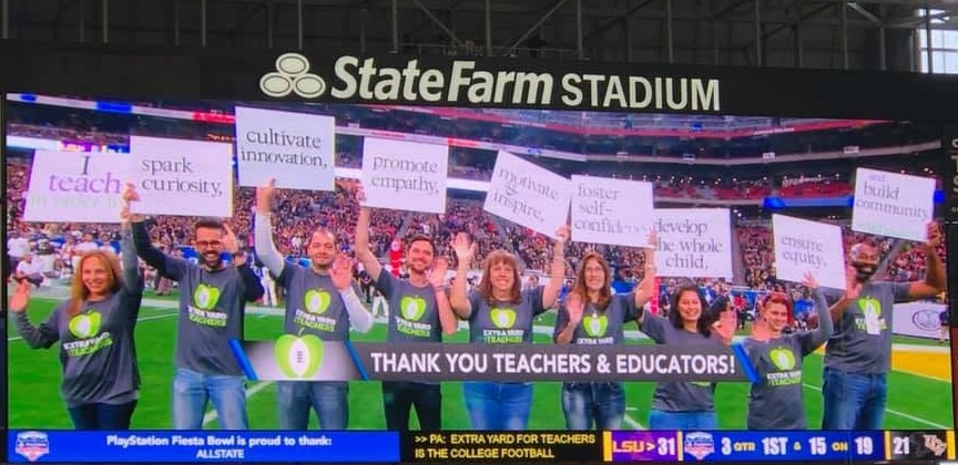 Ben (center-left), holding a sign that says promote empathy, alongside 2019 Arizona Teacher of the Year finalists on the field at the 2019 Arizona Fiesta Bowl